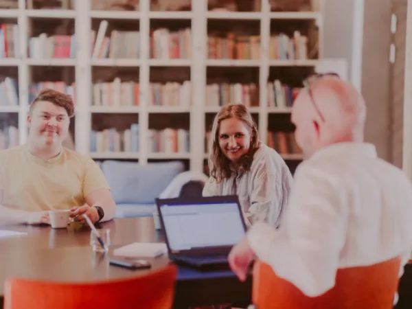 Iloiset tietotyöläiset neuvottelupöydän ääressä.