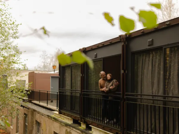 Nainen katselee kattohuoneiston ikkunasta avautuvaa maisemaa.