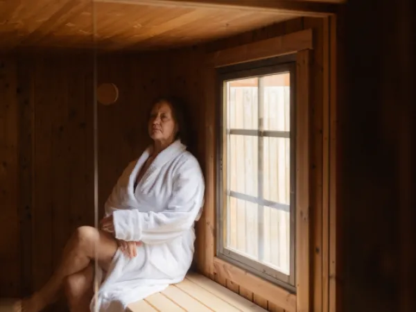 Hotel Mathildedalin aula, jossa nainen lukee kirjaa nojatuolissa.