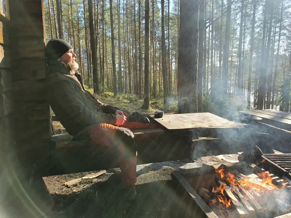 Mies istuu nuotion äärellä