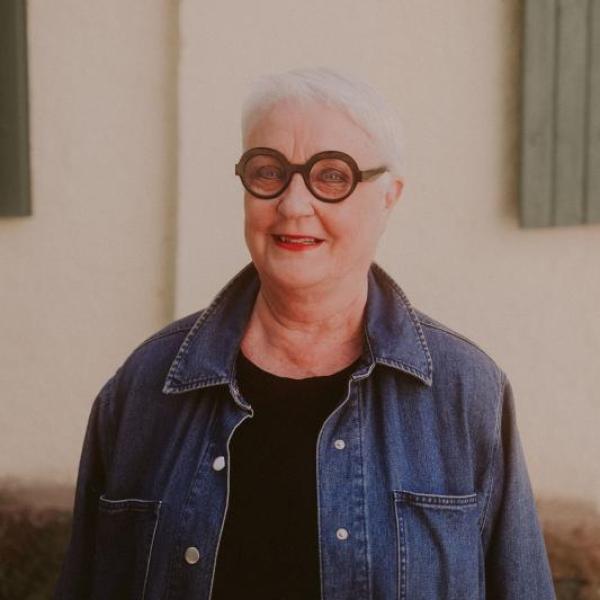 Farkkutakkiin pukeutunut nainen hymyilee.